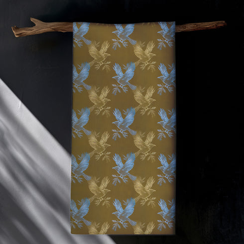 Set of four golden cloth napkins featuring alternating powder blue and metallic gold ravens in flight, sized 18x18 inches.